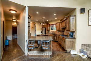 Kitchen featuring stone counters, backsplash, dark tile flooring, a center island, and stainless steel appliances