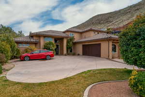 Mediterranean / spanish-style house with garage, a mountain view, and a front lawn