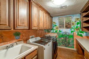 Washroom featuring washer / dryer, a textured ceiling, and light tile floors