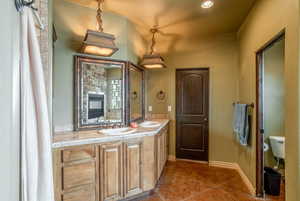 Bathroom with double vanity, mirror, and tile flooring