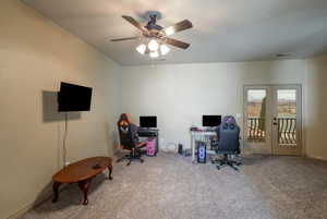 Home office featuring light carpet, french doors, ceiling fan, and TV