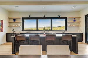 Interior space featuring a center island, a kitchen bar, light wood-type flooring, and gray cabinetry