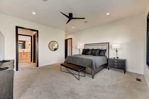 Carpeted bedroom with ceiling fan and ensuite bath