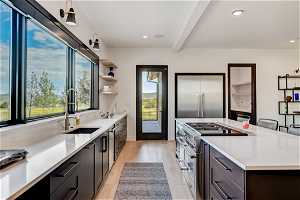 Kitchen with sink, a breakfast bar area, light hardwood / wood-style flooring, high end stove, and beamed ceiling
