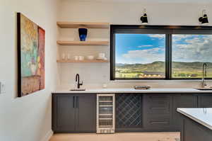 Kitchen with sink, light wood-type flooring, beverage cooler, and gray cabinetry