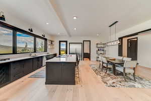 Kitchen with beamed ceiling, hanging light fixtures, an inviting chandelier, sink, and light hardwood / wood-style floors