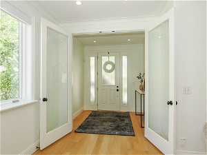 Foyer entrance featuring ornamental molding, a wealth of natural light, and light hardwood floors