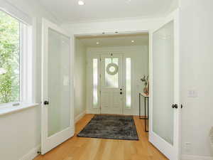 Foyer entrance featuring ornamental molding, a wealth of natural light, and light hardwood floors