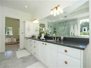 Bathroom with a tile shower, vanity with extensive cabinet space, mirror, and light tile floors