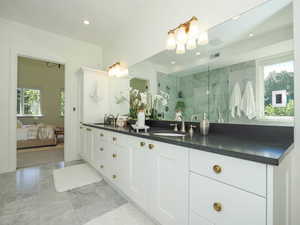 Bathroom with a tile shower, vanity with extensive cabinet space, mirror, and light tile floors