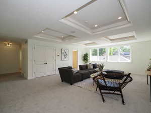 Carpeted living room featuring a raised ceiling