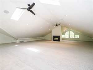 Bonus room with ceiling fan, light carpet, and vaulted ceiling with skylight