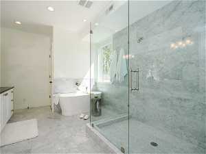 Bathroom featuring separate shower and tub, light tile floors, tile walls, and vanity