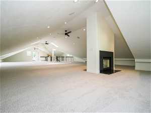 Additional living space with lofted ceiling, light carpet, a fireplace, and ceiling fan