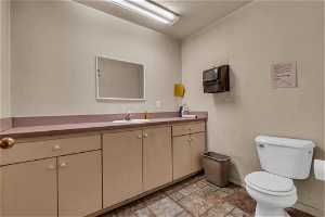 Half bathroom with tile flooring, mirror, toilet, and vanity