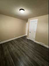 Unfurnished room with dark vinyl flooring and a textured ceiling