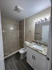 Bathroom featuring a textured ceiling, a tile shower, oversized vanity, and mirror