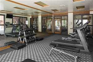 Exercise room featuring crown molding, carpet flooring, and a textured ceiling