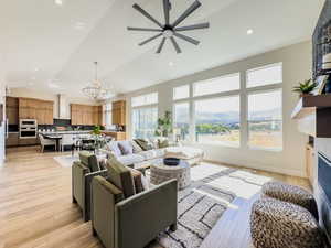 Living room with ceiling fan with notable chandelier, a mountain view, and light wood-type flooring