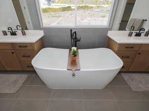 Bathroom featuring vanity, mirror, a wealth of natural light, a tub, tile walls, and light tile floors