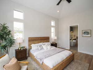 Bedroom featuring multiple windows, vaulted ceiling, a high ceiling, and light hardwood flooring