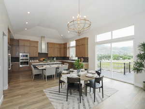 Wood floored dining space featuring a chandelier, a high ceiling, and lofted ceiling