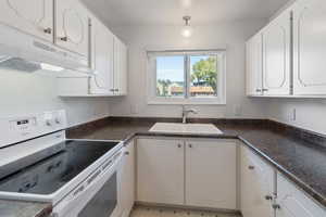 Kitchen with white cabinetry, sink, and white electric stove