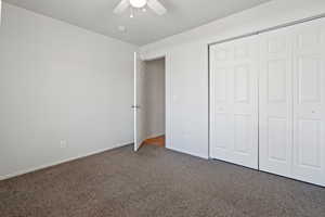 Unfurnished bedroom featuring carpet floors, ceiling fan, and a closet