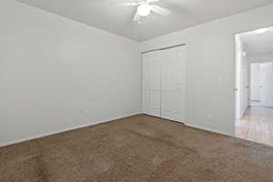 Unfurnished bedroom featuring light carpet, ceiling fan, and a closet