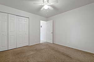 Unfurnished bedroom featuring light carpet, ceiling fan, and a closet