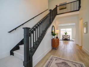 Staircase featuring a towering ceiling and light hardwood / wood-style floors