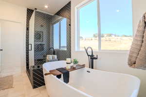 Bathroom with tile patterned flooring, independent shower and bath, a healthy amount of sunlight, and sink