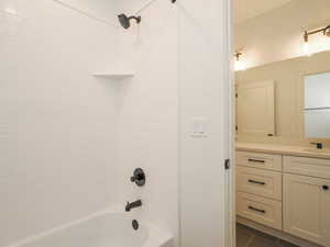 Bathroom with tile floors, tiled shower / bath combo, and vanity