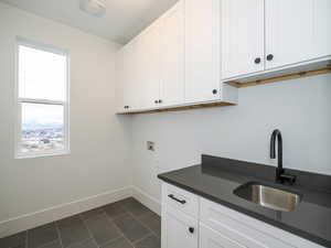 Washroom featuring sink, cabinets, dark tile flooring, and washer hookup