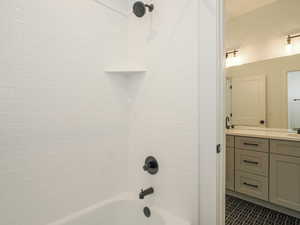 Bathroom featuring tiled shower / bath, vanity, and tile flooring