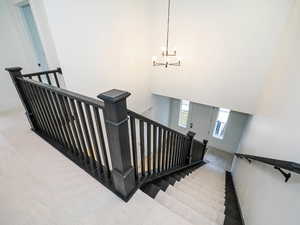 Stairway with a chandelier, a towering ceiling, and light colored carpet