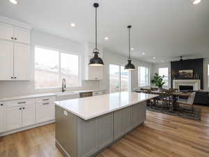 Kitchen featuring a kitchen island, light wood-type flooring, gray cabinetry, and hanging light fixtures