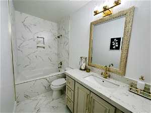 Full bathroom featuring large vanity, tiled shower / bath combo, a textured ceiling, toilet, and tile flooring