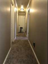 Hallway featuring dark carpet and ornamental molding