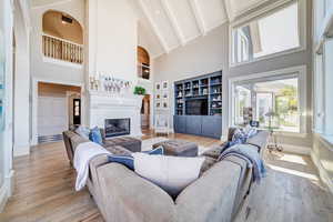 Living room with a high ceiling, light hardwood floors, lofted ceiling, a fireplace and an abundance of natural light that provide the panoramic views of the city and mountains.