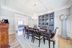 Formal dining room with coffered ceiling and light hardwood floors.