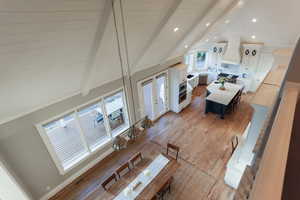 Hardwood floored dining space with a high ceiling and a vaulted ceiling.