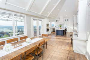 Hardwood floored dining space with a high ceiling and a vaulted ceiling.