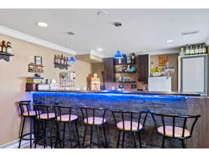 Bar with decorative light fixtures, pool, dark granite-like countertops, and crown molding