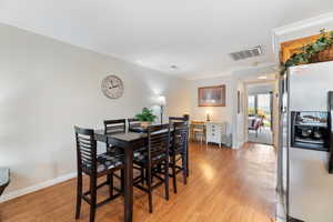 Wood floored dining area featuring ornamental molding