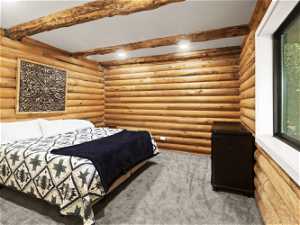 Main Level Bedroom Suite Carpeted bedroom featuring log walls and beam ceiling
