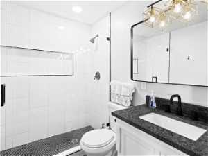 Main Level Master Suite Bathroom featuring a tile shower, mirror, and vanity