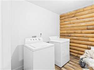 Washroom featuring light hardwood flooring, log walls, and washer and dryer