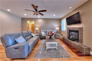 Hardwood floored living room with a fireplace and ceiling fan