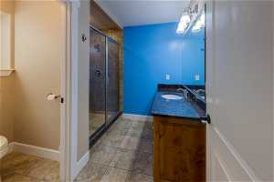 Bathroom with an enclosed shower, oversized vanity, mirror, and light tile floors